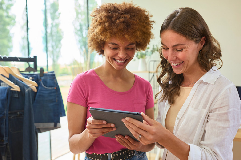 Two people in a clothing store looking at a tablet together